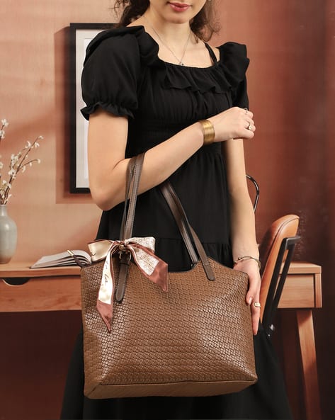 Model carrying a brown tote bag and wearing gold jewellery