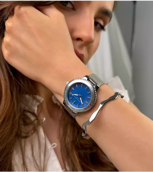 Woman wearing a silver watch with a blue dial and a silver bangle